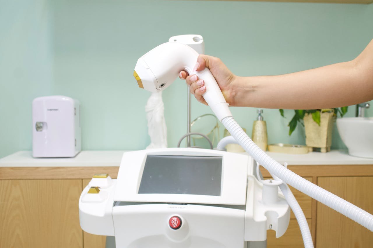 our-story Close-up of a hand holding a laser hair removal device in a clinic setting.